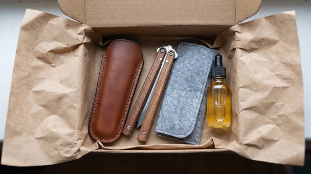 Handmade balisong butterfly knife packed in a box with a fitted leather sheath, a cloth pouch and a small bottle of knife oil