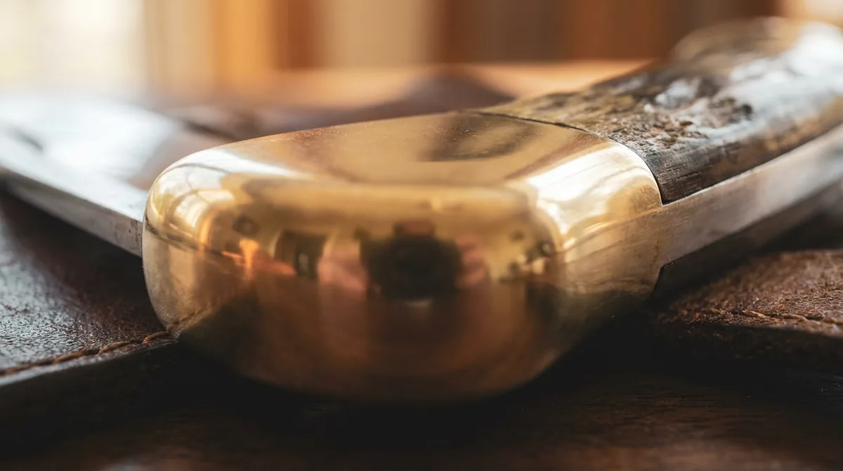 Macro of a bare mirror polished blank brass bolster on a butterfly knife handle