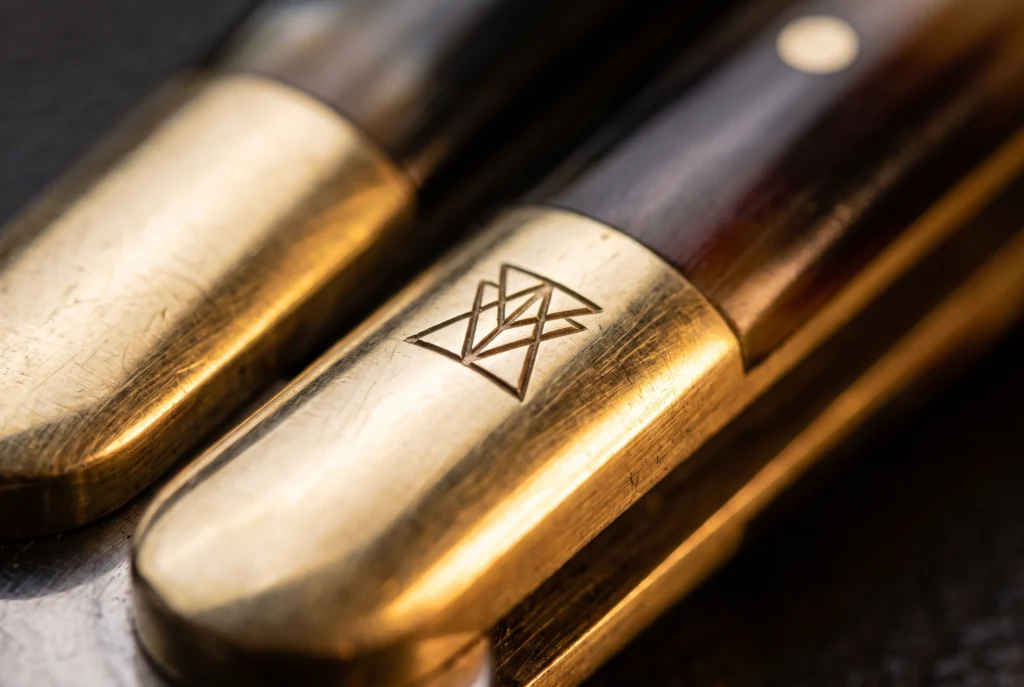 A logo engraved into the polished brass bolster of a butterfly knife