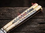Monarch balisong butterfly knife closed at an angle showing the bone handle scales and brass bolsters