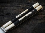 Close up of the Mongrel balisong butterfly knife kamagong wood handle with pale inlay and brass bolsters