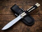 Mongrel balisong butterfly knife closed beside its black leather belt sheath
