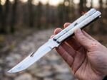 Moth Filipino balisong butterfly knife held open in hand outdoors, stainless steel and bone handle