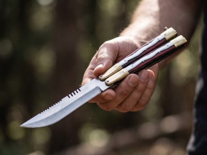 Neanderthal Filipino balisong butterfly knife held open in hand outdoors, micarta handle with brass pins